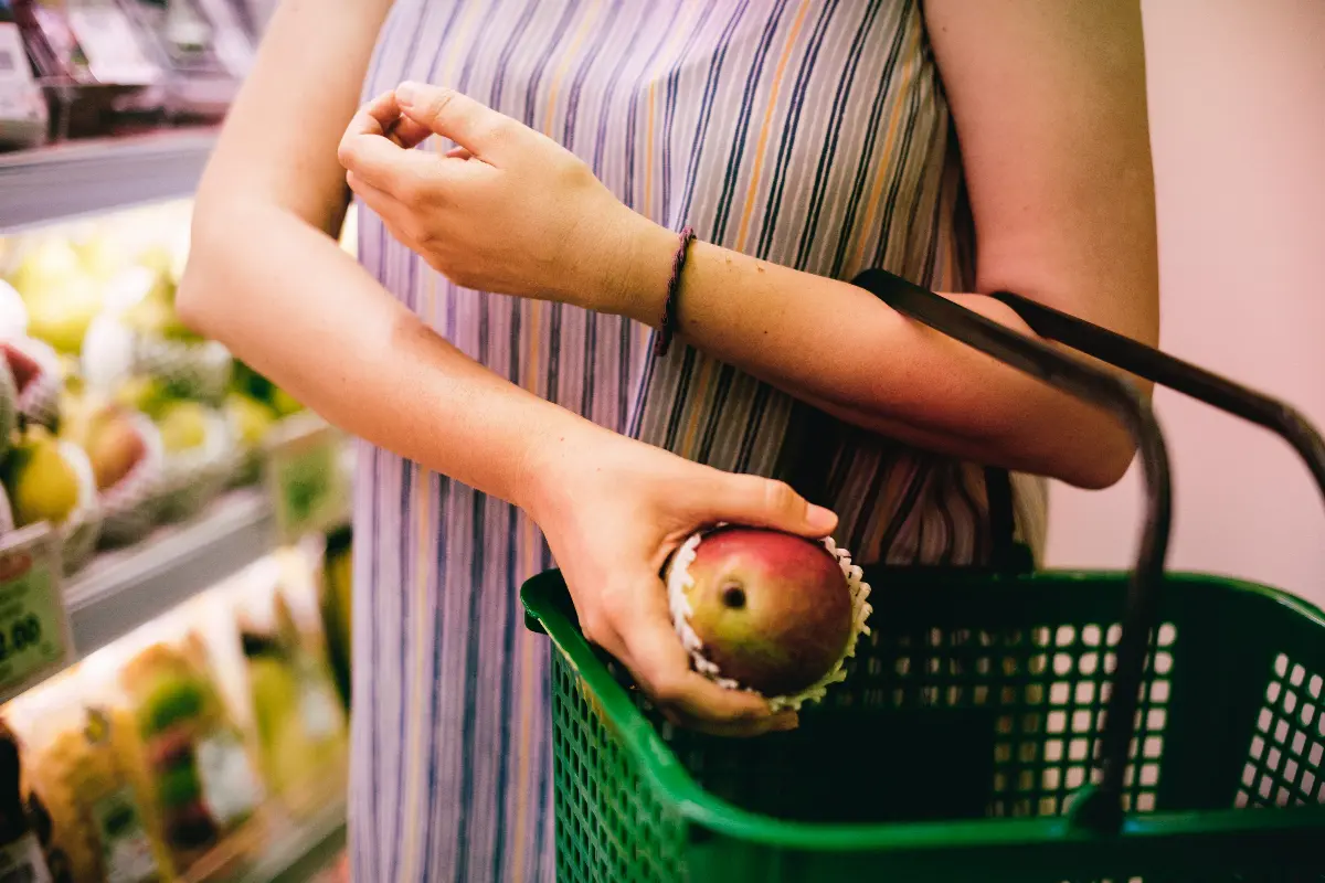 Donna che mette un mango del carrello